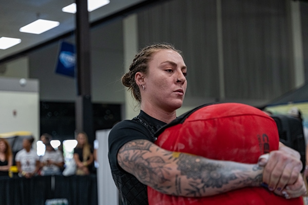 Shannon Palmer carrying a sandbag with an intense look