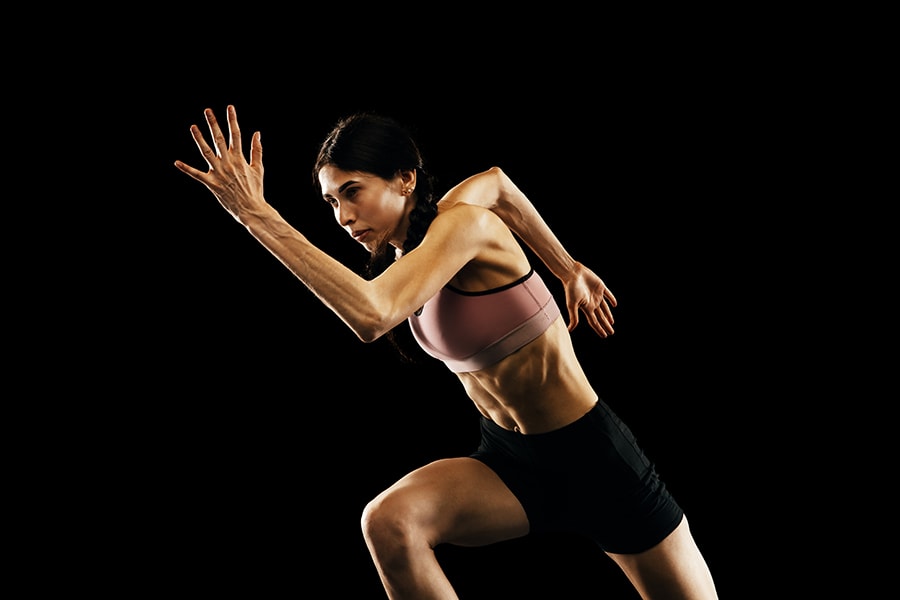 Female athlete sprinting in black background